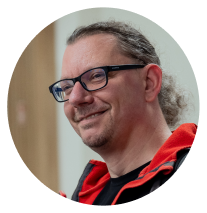 Man wearing glasses, long hair tied back,